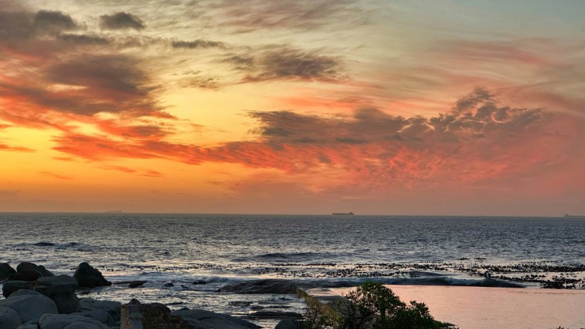 a sunset over the ocean with a boat in the distance