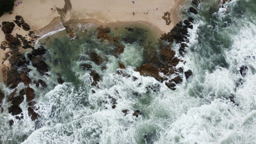 an aerial view of a beach with waves crashing onto the shore