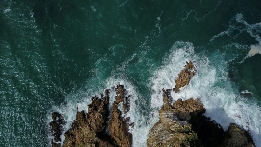 an aerial view of the ocean and rocks rfm