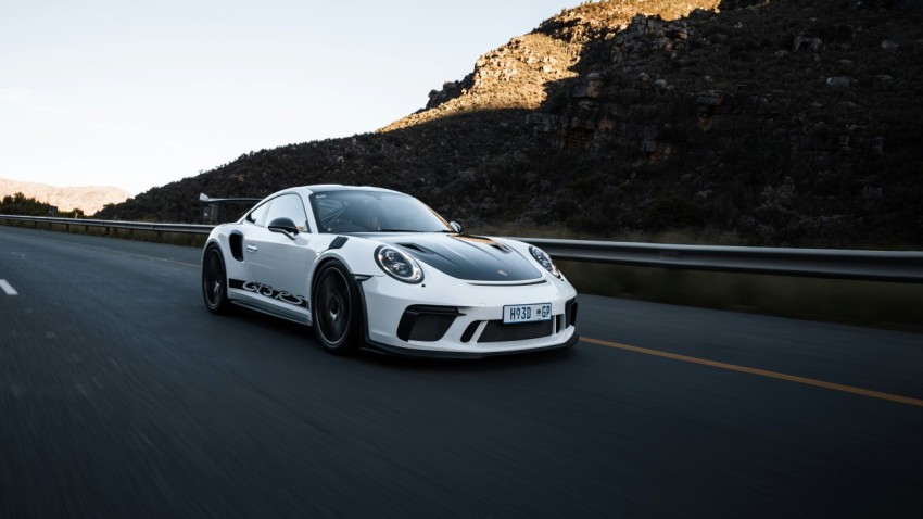 a white sports car driving down the road