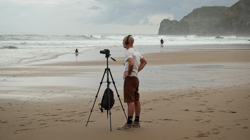 a man standing on top of a beach next to a camera