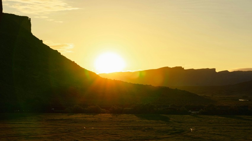 the sun is setting over a hill with a clock tower