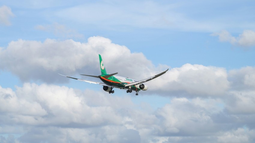 an airplane flying in the sky with clouds in the background