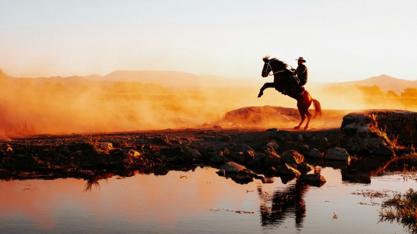 a person on a horse jumping over a body of water