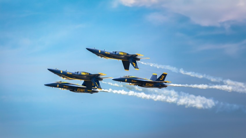 a group of fighter jets flying through a blue sky