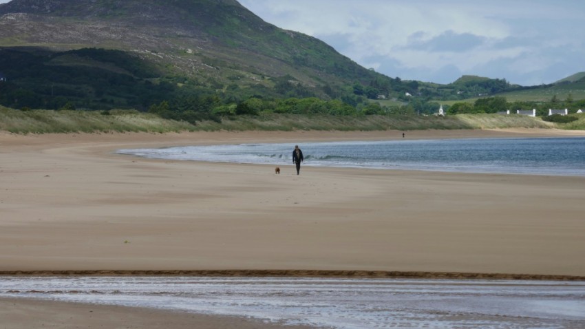 a person walking on a beach next to a body of water Getf