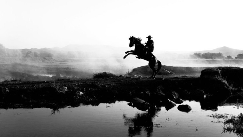 a black and white photo of a person riding a horse