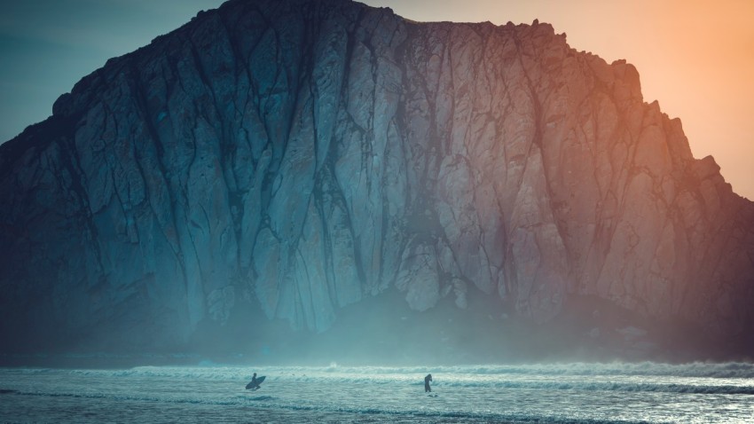 surfer on body of water near sea cliff during daytime ZvVhWYA