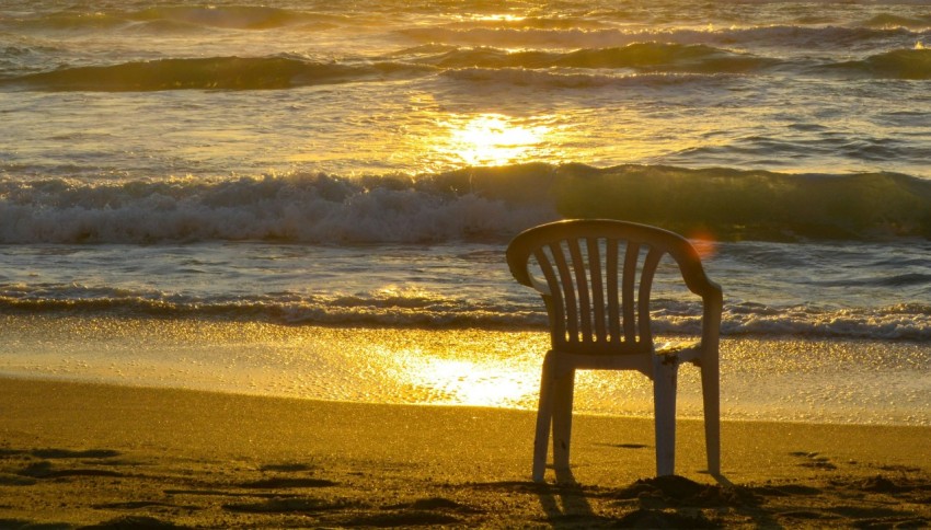 a chair sitting on a beach next to the ocean