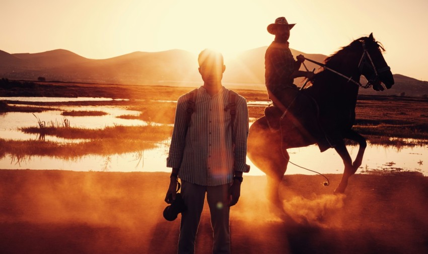 a man standing next to a horse in a field