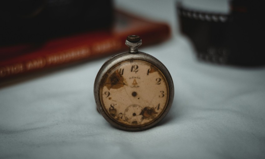 a pocket watch sitting on a table next to a book