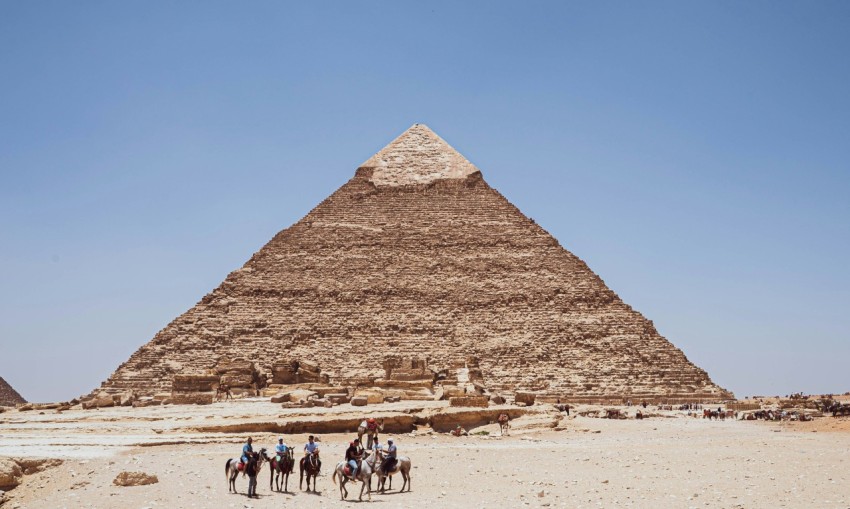 a group of people riding camels in front of a pyramid