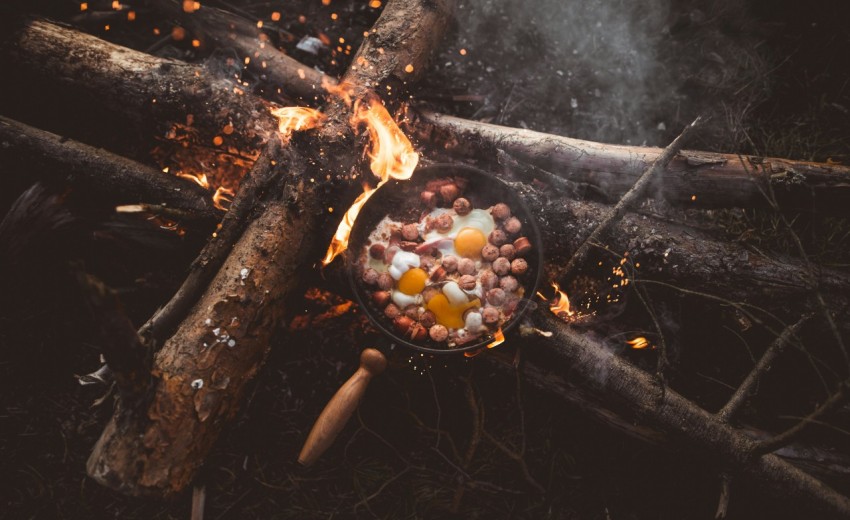 frying pan with food on lit firewood L8DBG5