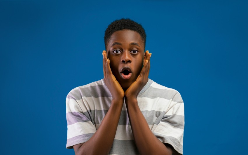 a boy making a surprised face with his hands