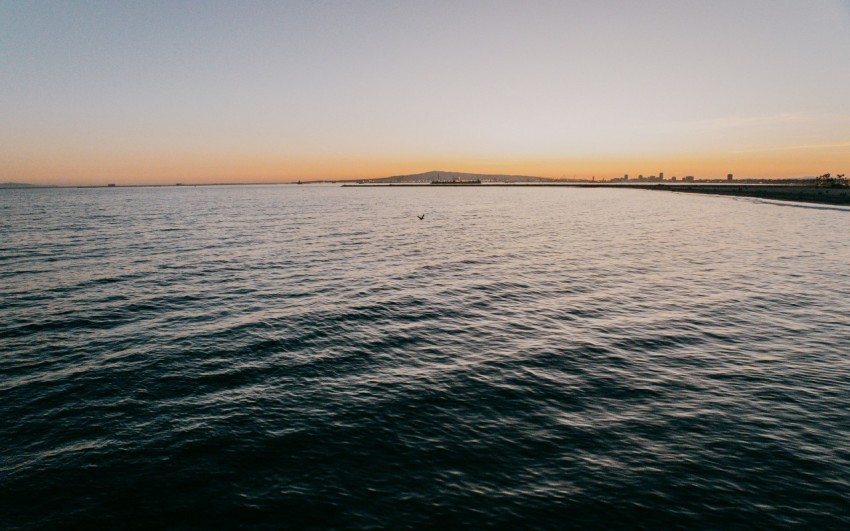 a large body of water with a sunset in the background