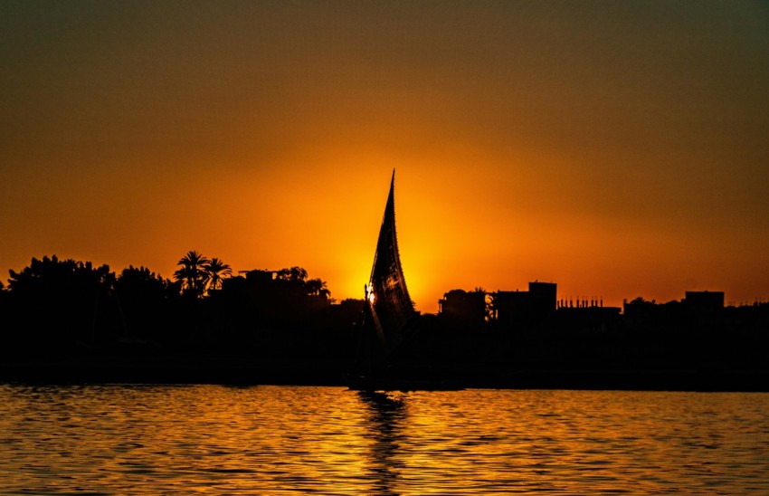 a sailboat in the water at sunset