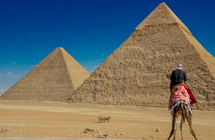 a person riding a camel in front of a pyramid