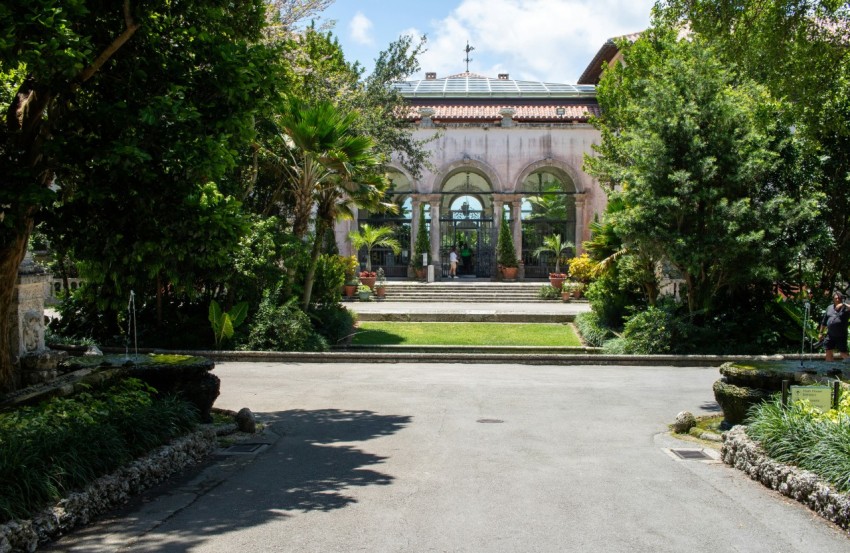 a driveway leading to a large building surrounded by trees