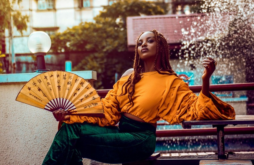 a woman sitting on a bench holding a fan