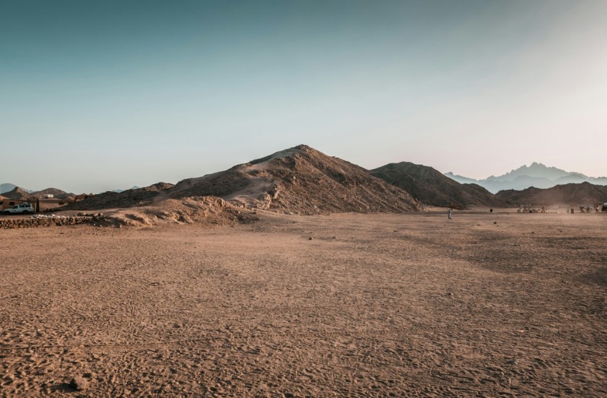 a dirt field with mountains in the background