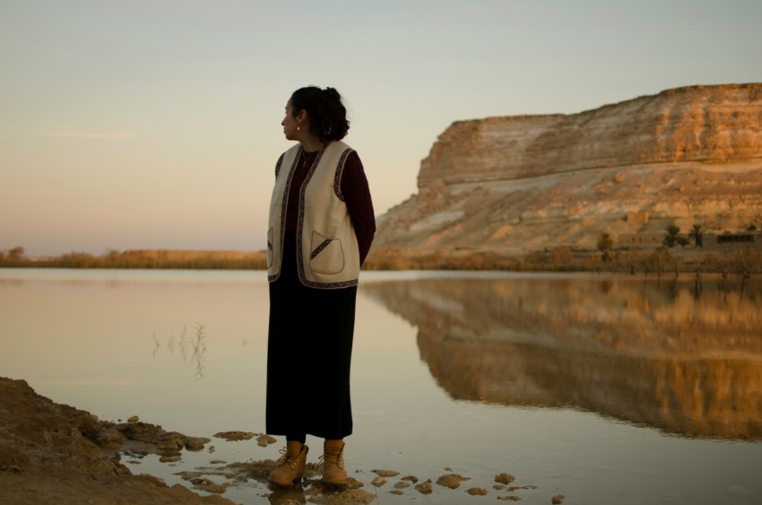 a woman standing in front of a body of water