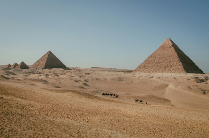 a group of people riding camels across a desert