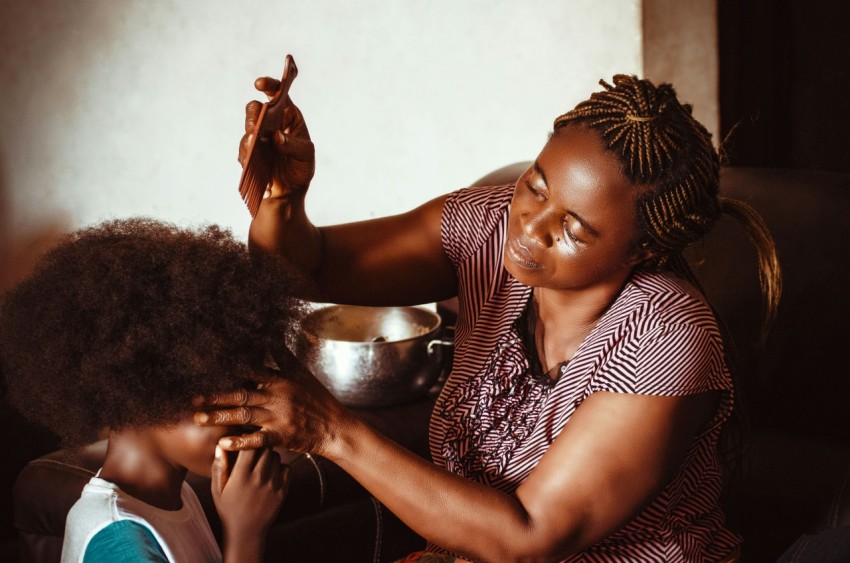 a woman sitting next to a little girl who is brushing her hair 5Z