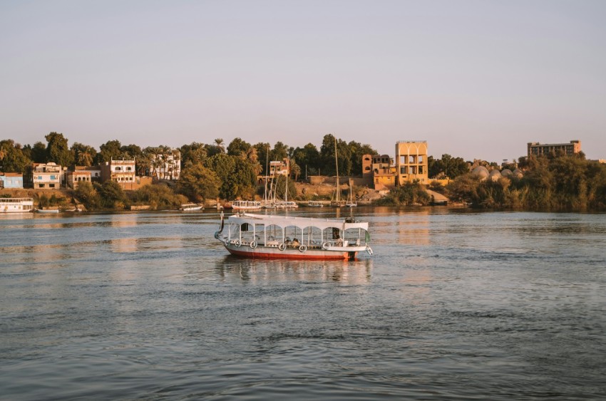 a boat floating on top of a river next to a lush green hillside