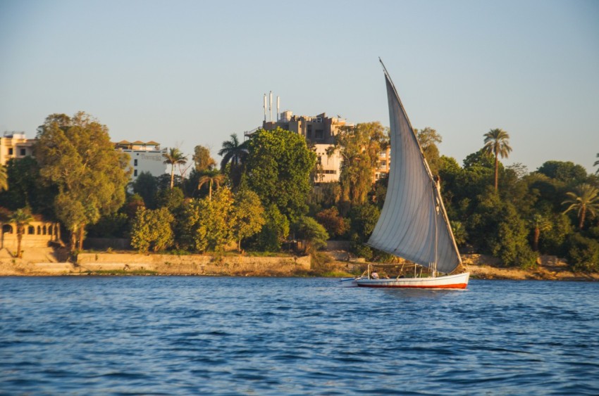 a sailboat on the water with a city in the background