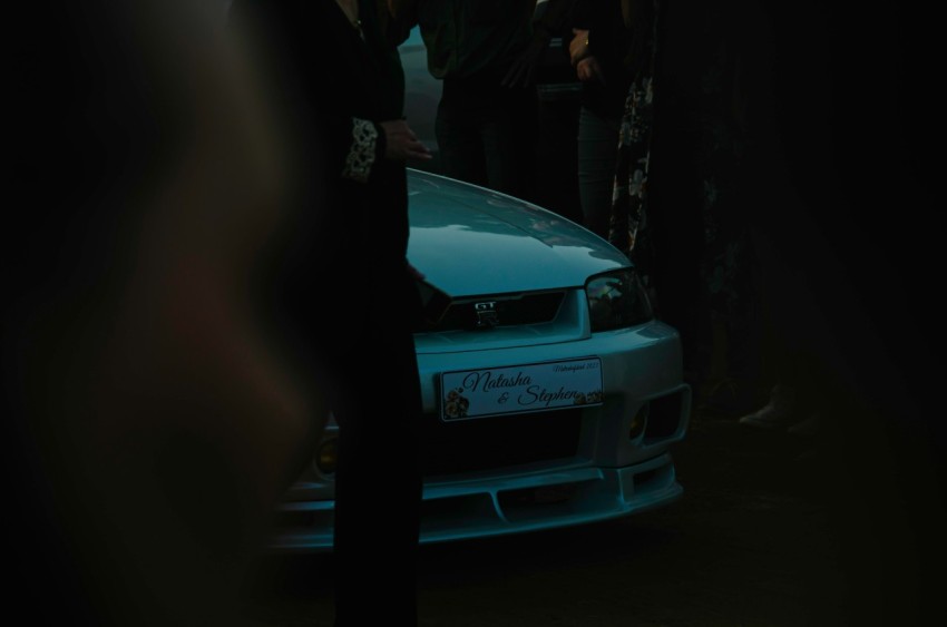 a group of people standing around a white car