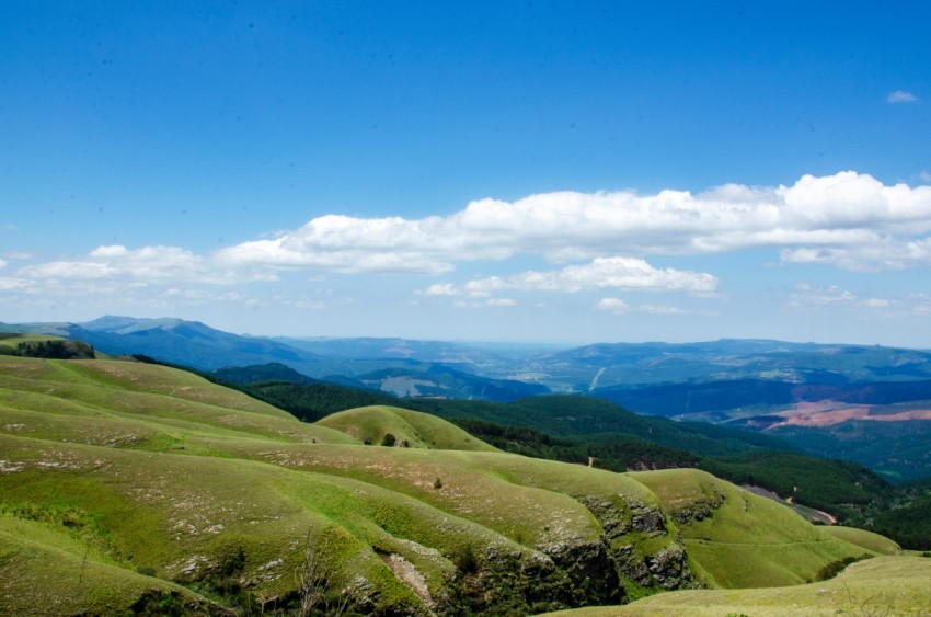 green grass field and mountains under blue sky during daytime