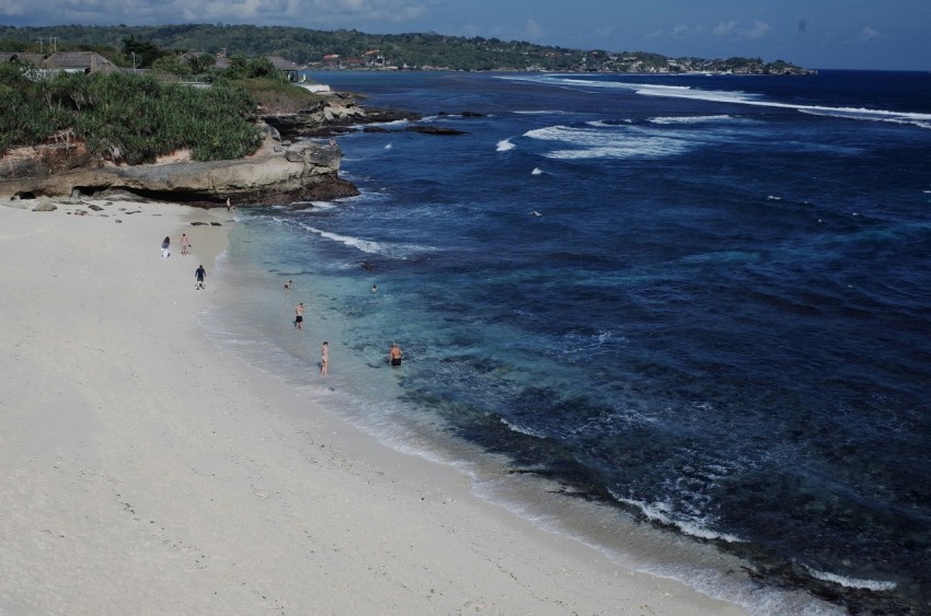 a beach with people walking on it next to the ocean