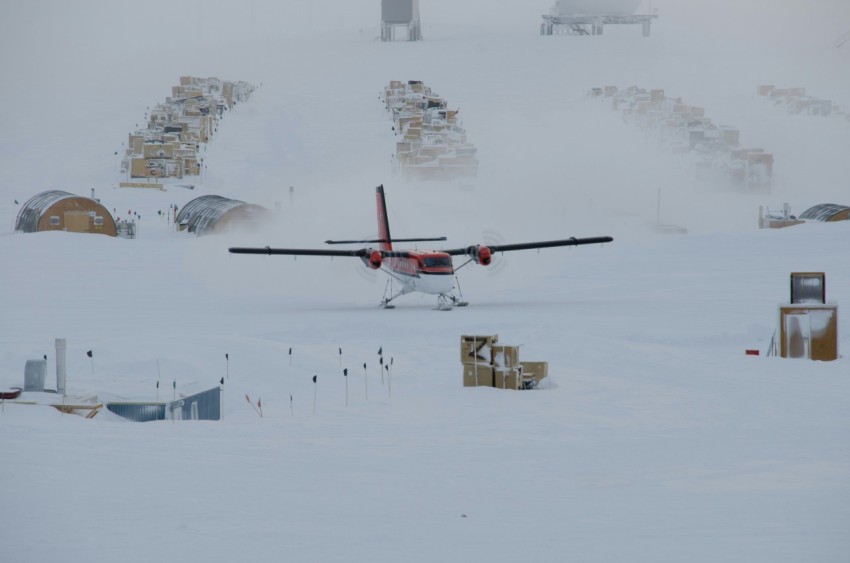 white and brown biplane on snow covered field