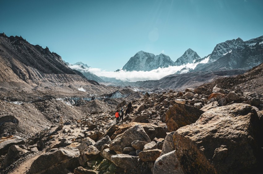 a man hiking up a rocky mountain with mountains in the background