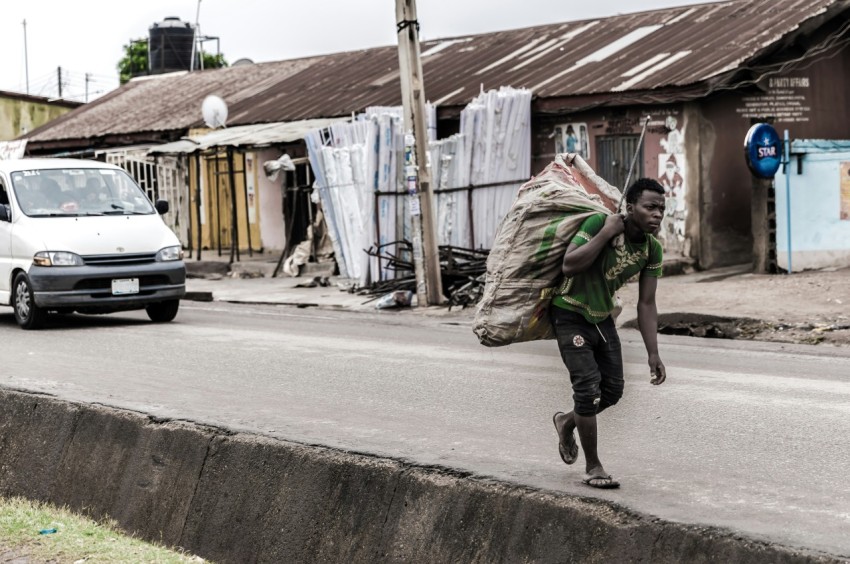 man holding brown sack beside pave road V