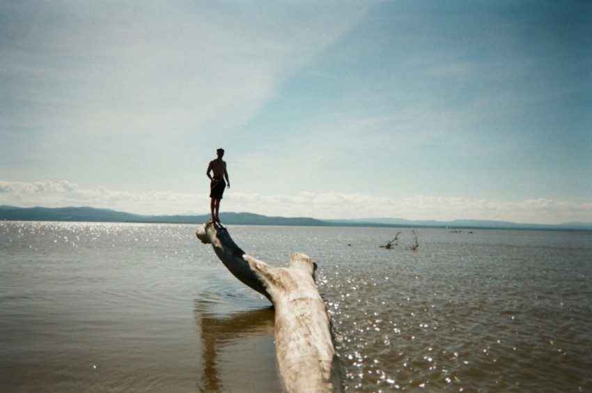 woman in black jacket and black pants standing on brown sand near sea during daytime