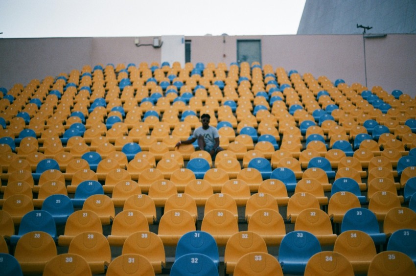 person sitting in the middle of chair lot during daytime