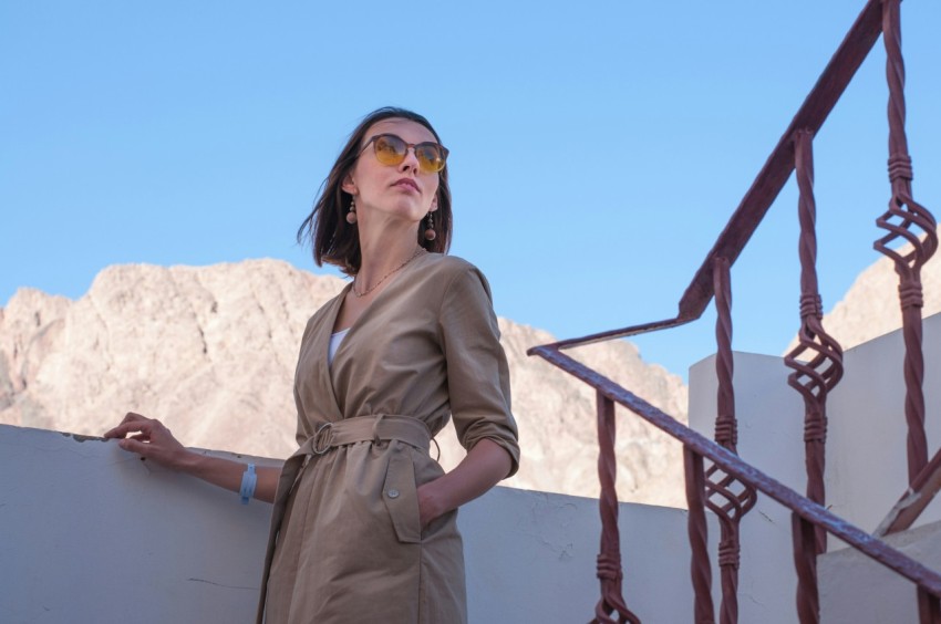 a woman in a trench coat leaning against a wall