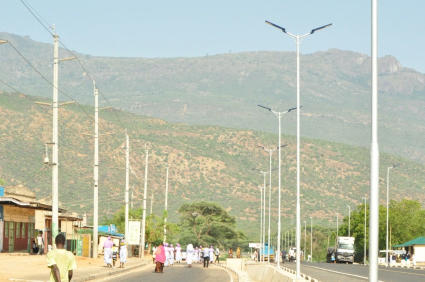 a group of people walking on a road with tall white poles P5c0dvj