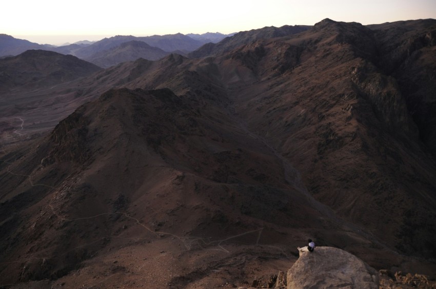 a person sitting on top of a mountain overlooking a valley