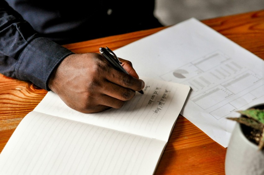 a hand holding a pen over a notebook