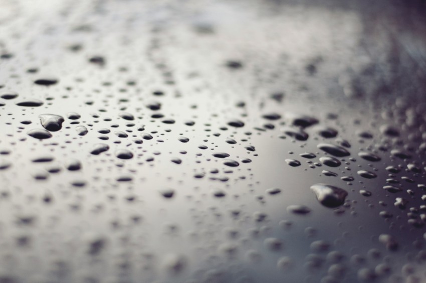 macro photography of water drops on black glass surface