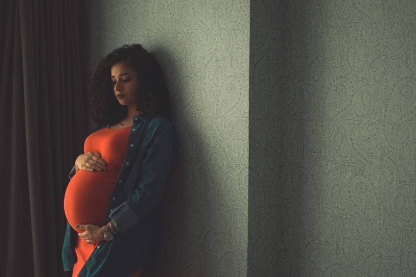 a pregnant woman leaning against a wall