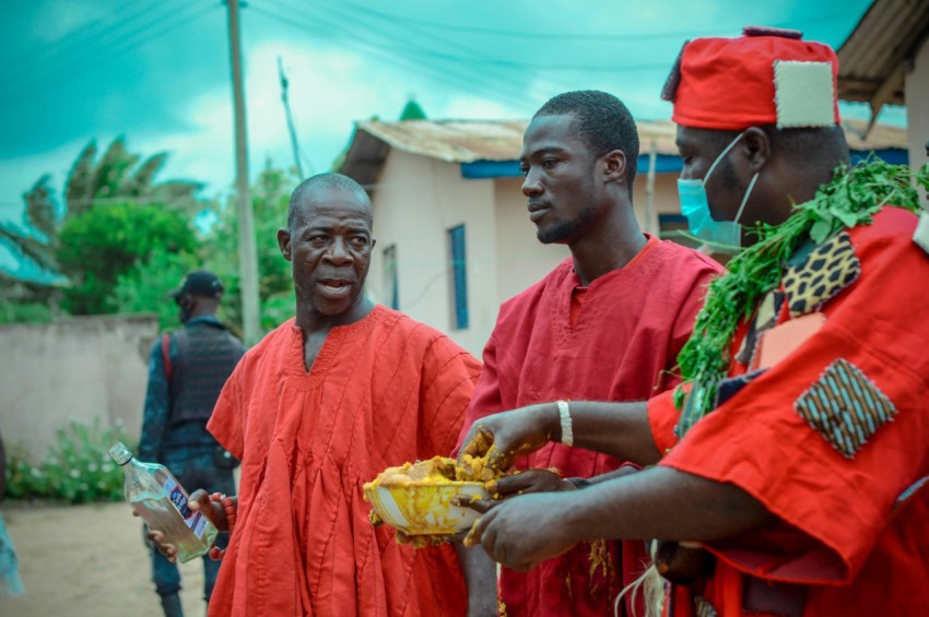 man in orange robe holding yellow vegetable