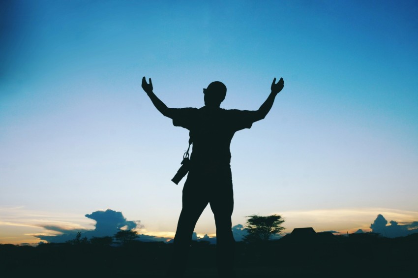 a silhouette of a man raising his arms in the air