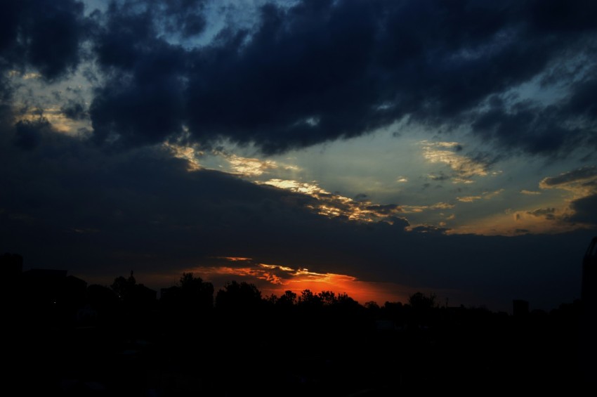 the sun is setting behind a dark cloud filled sky NV