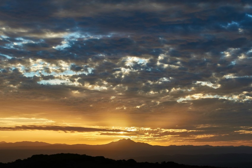 the sun is setting over a mountain range