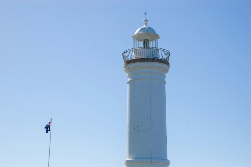 a white lighthouse with a blue sky in the background