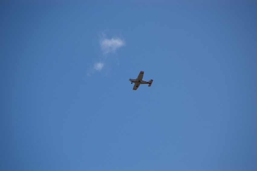 a plane flying in the sky with a cloud in the background OvfKEUoeq