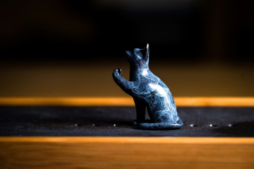 a cat figurine sitting on top of a wooden table